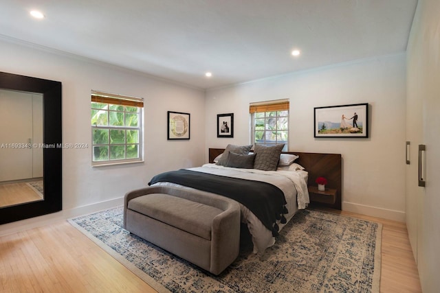 bedroom with light hardwood / wood-style floors, multiple windows, and crown molding