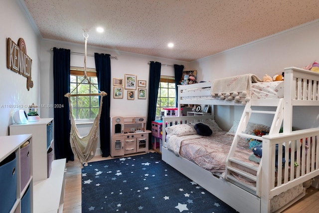 bedroom with hardwood / wood-style flooring, a textured ceiling, crown molding, and multiple windows