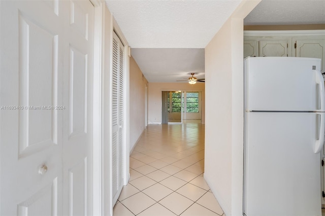 kitchen with a textured ceiling, ceiling fan, white fridge, and light tile patterned floors