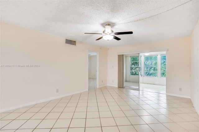 tiled empty room featuring ceiling fan and a textured ceiling