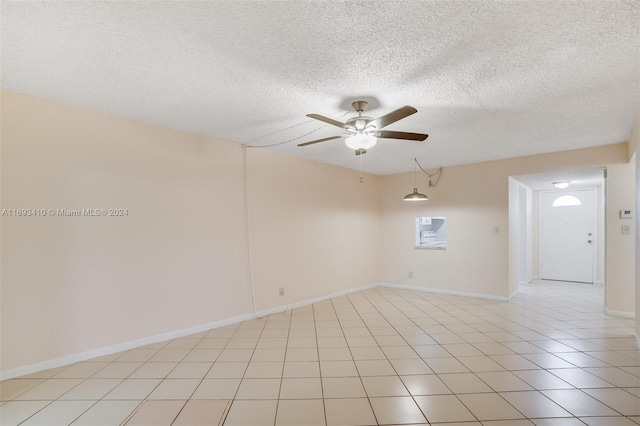 tiled empty room with ceiling fan and a textured ceiling