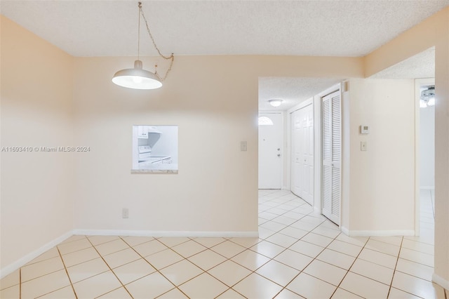 tiled empty room featuring a textured ceiling and washer / clothes dryer