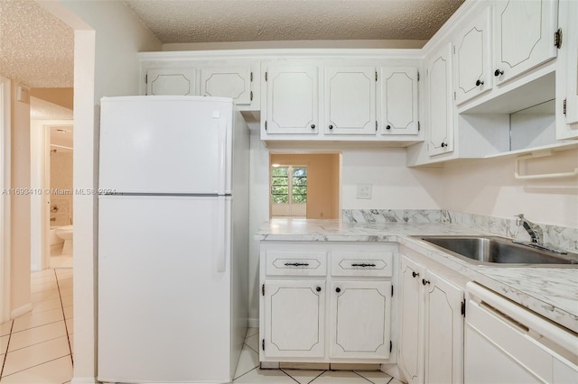 608 SW Natura Blvd Unit 311, Deerfield Beach, FL 33441 - kitchen featuring white appliances, a textured ceiling, light tile patterned floors, light countertops, and white cabinetry