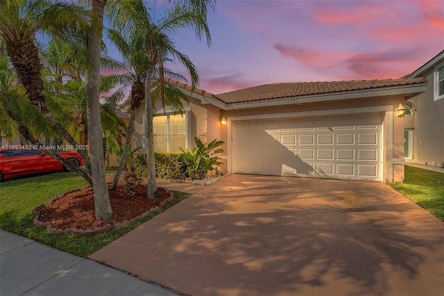 view of front of property with driveway, an attached garage, a tile roof, and stucco siding