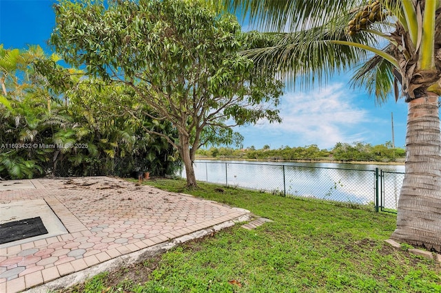 view of yard with a patio, a water view, fence, and a gate