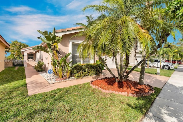 view of front of house featuring a front yard, driveway, an attached garage, and stucco siding