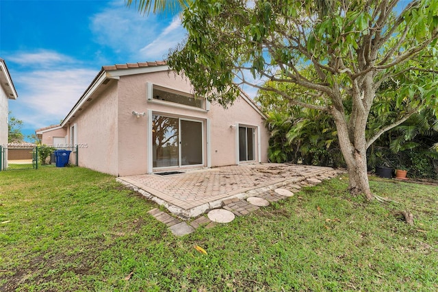 back of property featuring a patio, fence, a lawn, and stucco siding