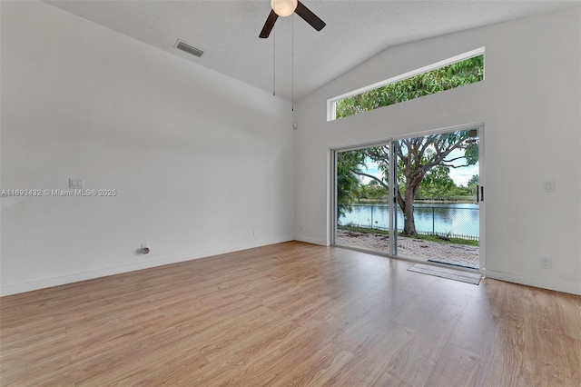 empty room with a water view, a ceiling fan, baseboards, visible vents, and light wood-type flooring