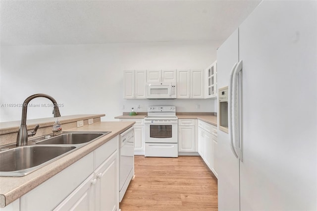 kitchen with white appliances, white cabinetry, light wood finished floors, and a sink