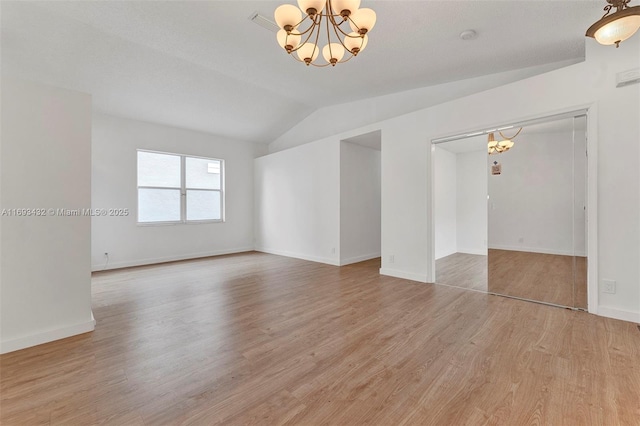 empty room with light wood finished floors, baseboards, vaulted ceiling, and a notable chandelier