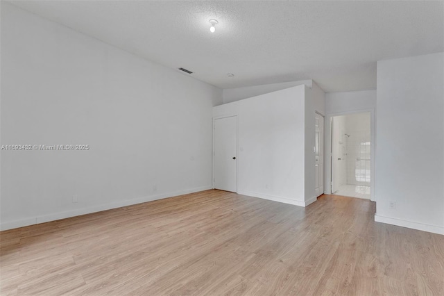 unfurnished bedroom with light wood-style flooring, visible vents, baseboards, and a textured ceiling