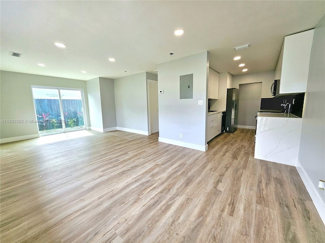 unfurnished living room featuring light wood-type flooring and electric panel