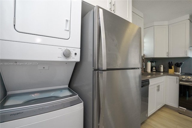 kitchen with white cabinets, stacked washer and clothes dryer, and appliances with stainless steel finishes