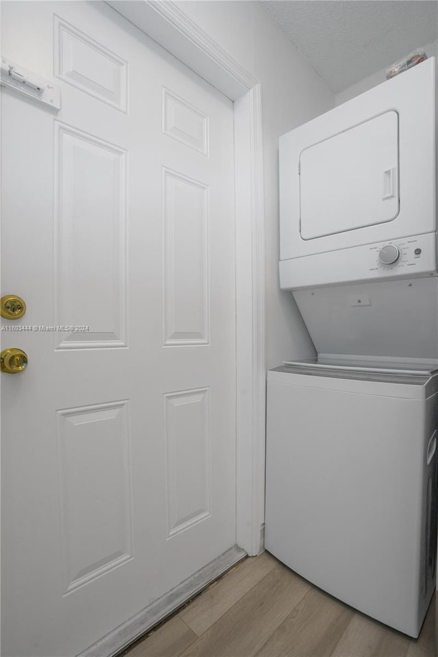 washroom with light wood-type flooring and stacked washer and clothes dryer