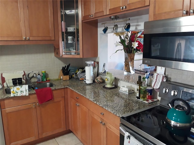 kitchen with stainless steel appliances, sink, light stone countertops, light tile patterned floors, and decorative backsplash