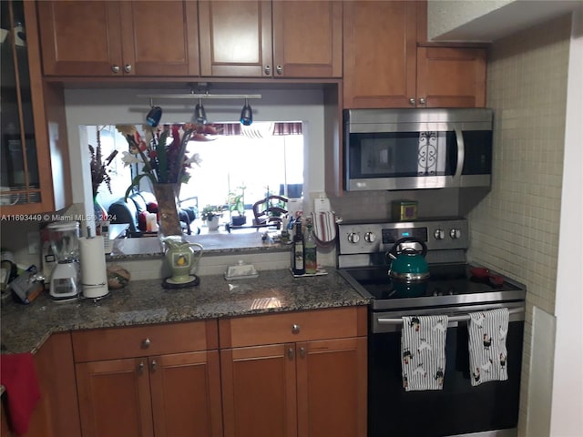 kitchen with stainless steel appliances, dark stone countertops, and decorative backsplash