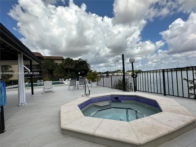 view of swimming pool featuring a hot tub and a water view