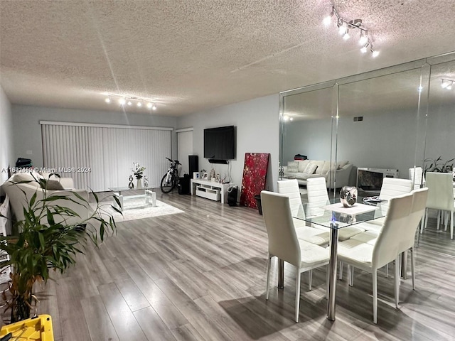 dining area with hardwood / wood-style flooring, track lighting, and a textured ceiling