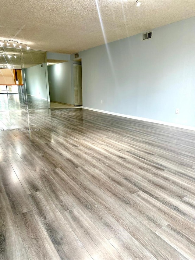 empty room with wood-type flooring and a textured ceiling