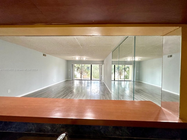 unfurnished room with hardwood / wood-style flooring and a textured ceiling