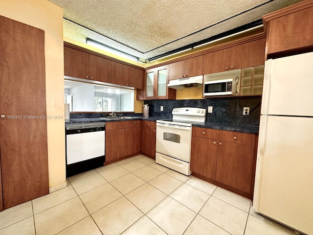 kitchen featuring decorative backsplash, white appliances, a textured ceiling, and light tile patterned floors