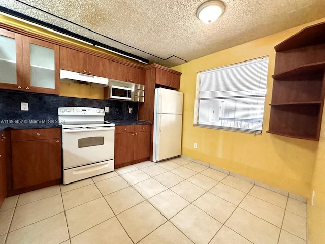 kitchen featuring a textured ceiling, tasteful backsplash, white appliances, and light tile patterned floors