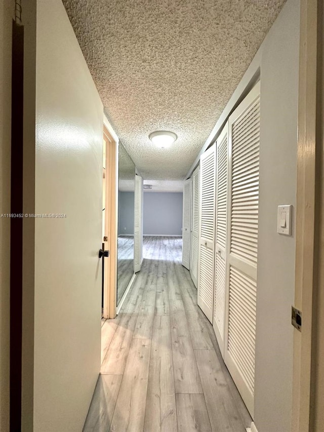 hallway featuring a textured ceiling and light hardwood / wood-style flooring