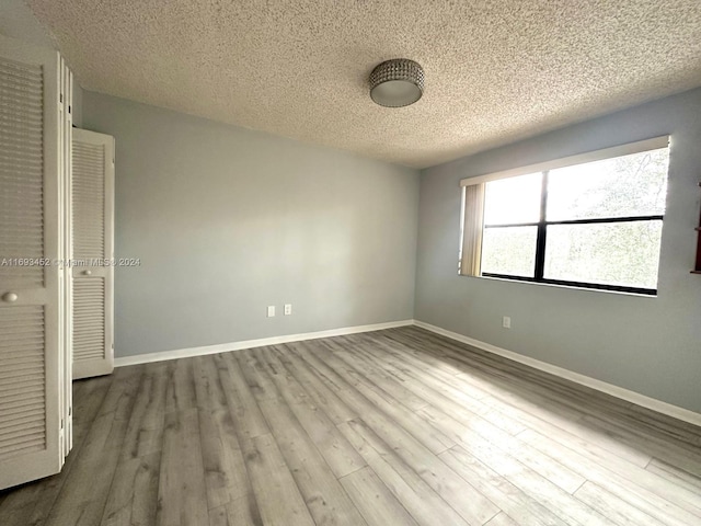 unfurnished bedroom with wood-type flooring, a textured ceiling, and a closet