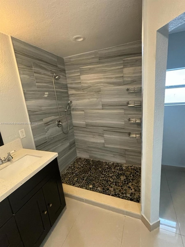 bathroom with tiled shower, vanity, a textured ceiling, and tile patterned floors