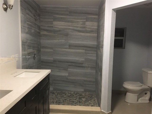 bathroom featuring toilet, vanity, and a tile shower