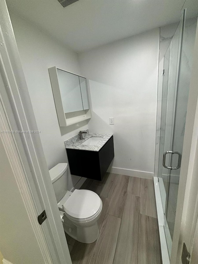 bathroom featuring hardwood / wood-style floors, an enclosed shower, vanity, and toilet