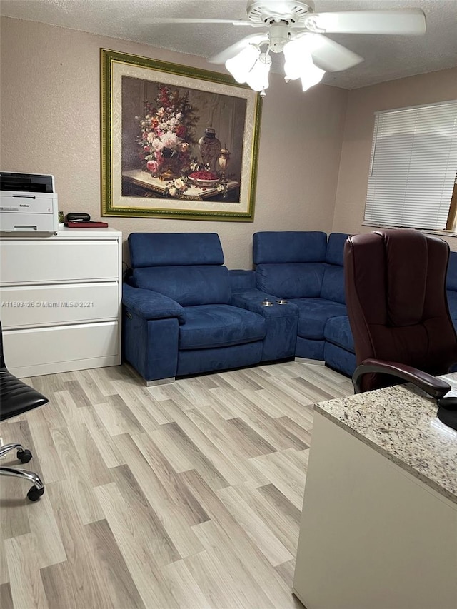 living room with a textured ceiling, light hardwood / wood-style floors, and ceiling fan