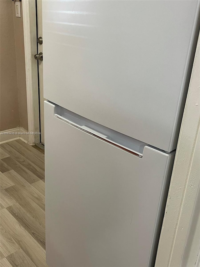 room details with light wood-type flooring and white fridge