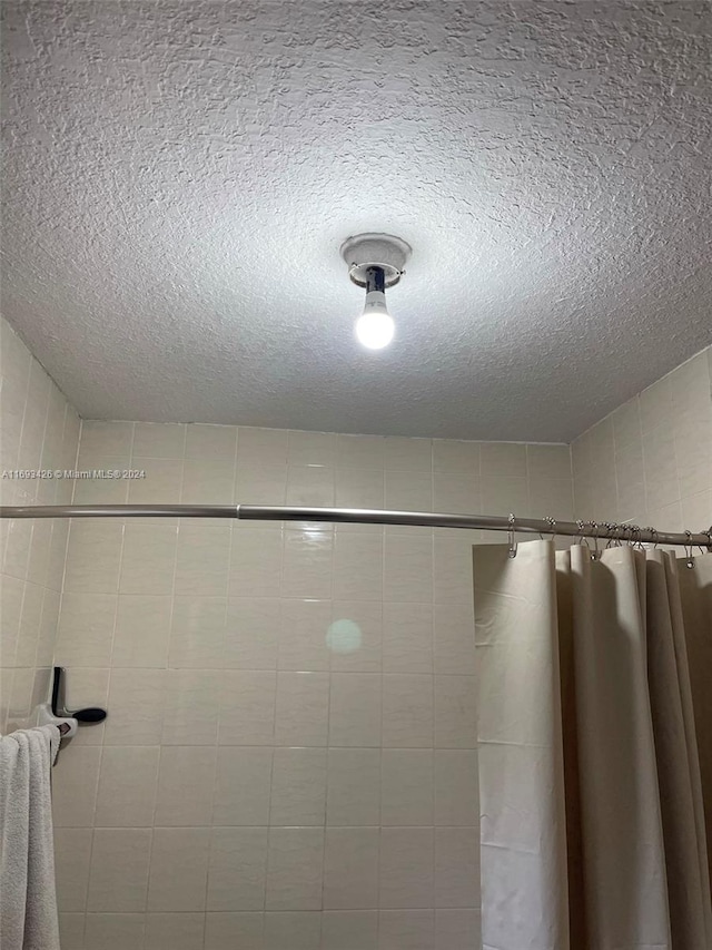 bathroom with a textured ceiling and a shower with shower curtain