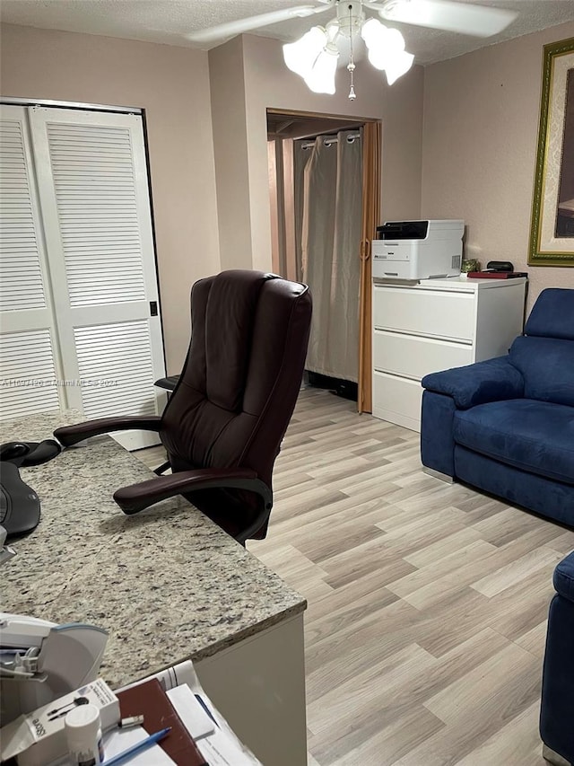 home office with a textured ceiling, light hardwood / wood-style flooring, and ceiling fan