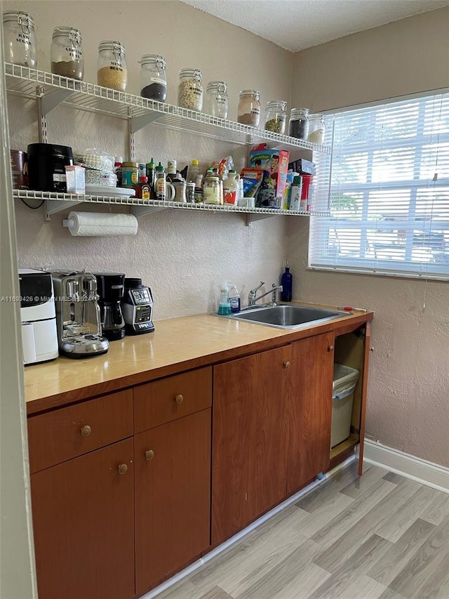 kitchen with a textured ceiling, light hardwood / wood-style floors, and sink