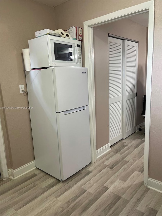 kitchen with white appliances and light hardwood / wood-style floors