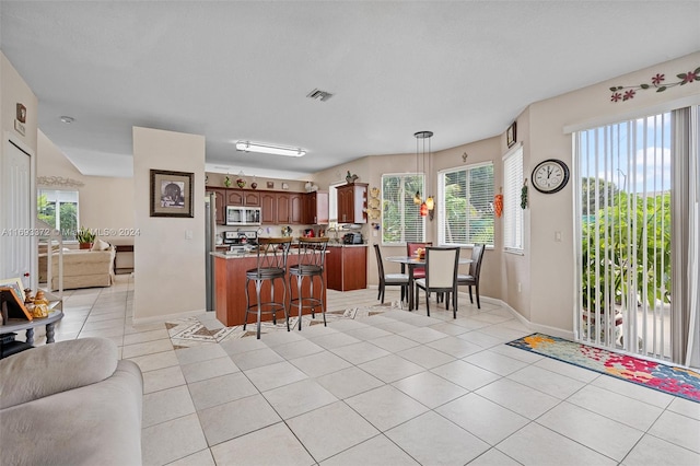 kitchen featuring stainless steel appliances, a breakfast bar area, plenty of natural light, and light tile patterned floors