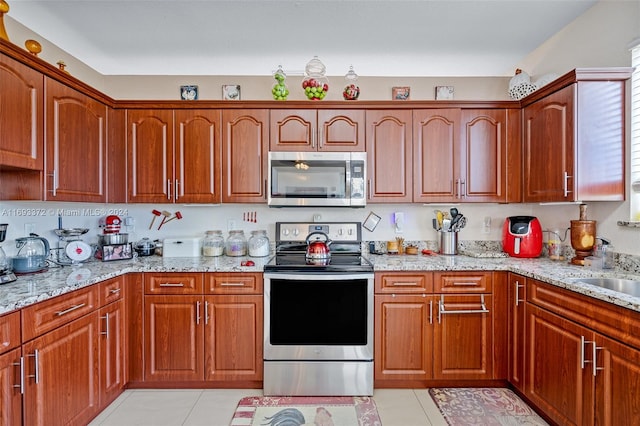 kitchen featuring light stone countertops, light tile patterned floors, and stainless steel appliances