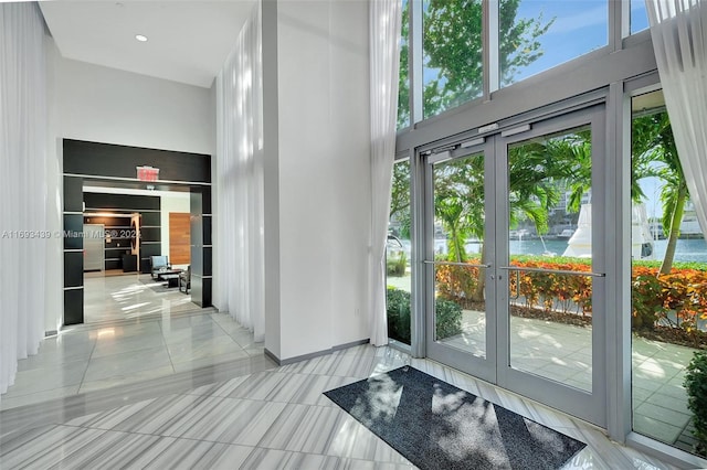 entryway featuring french doors, light tile patterned flooring, and a towering ceiling