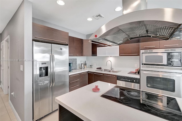 kitchen featuring stainless steel appliances, lofted ceiling, island range hood, dark brown cabinetry, and sink