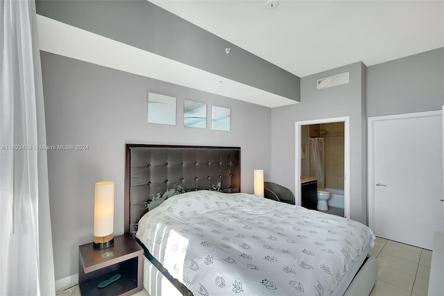 bedroom with ensuite bathroom and light tile patterned floors