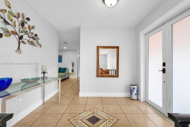 kitchen featuring light tile patterned floors, white cabinets, stainless steel fridge, and light stone countertops