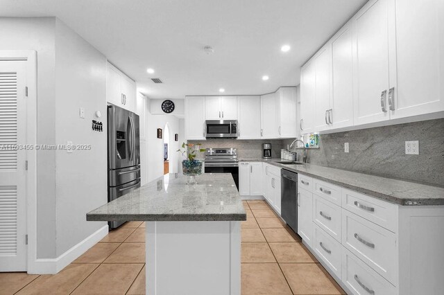 kitchen with tasteful backsplash, sink, light stone countertops, stainless steel appliances, and white cabinets