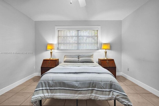 tiled bedroom featuring ensuite bath and ceiling fan