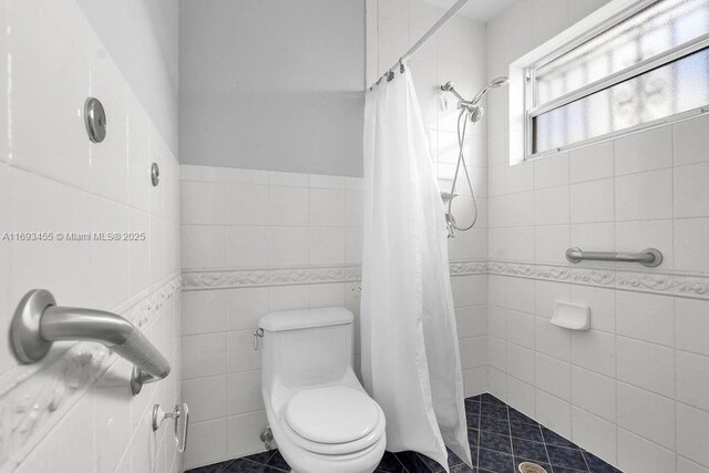 bathroom with toilet, a shower with shower curtain, and tile walls