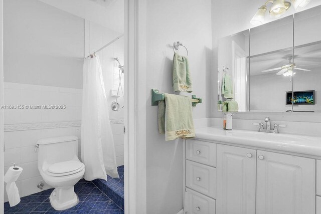 bathroom featuring toilet, ceiling fan, tile patterned flooring, a shower with curtain, and vanity