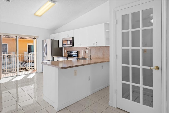 kitchen featuring appliances with stainless steel finishes, backsplash, light tile patterned floors, white cabinetry, and lofted ceiling