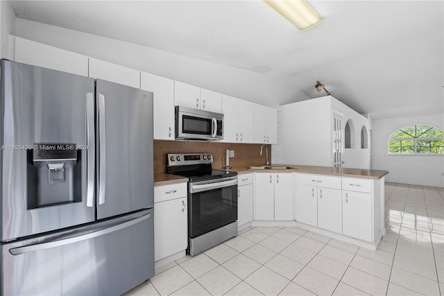 kitchen featuring sink, stainless steel appliances, backsplash, vaulted ceiling, and white cabinets