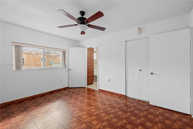 unfurnished bedroom featuring ceiling fan, dark parquet floors, ensuite bathroom, and a textured ceiling